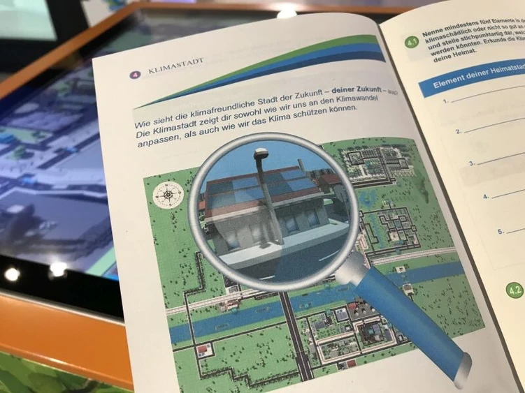 Eine Lupe ist in einem ge&ouml;ffneten Heft zu sehen.